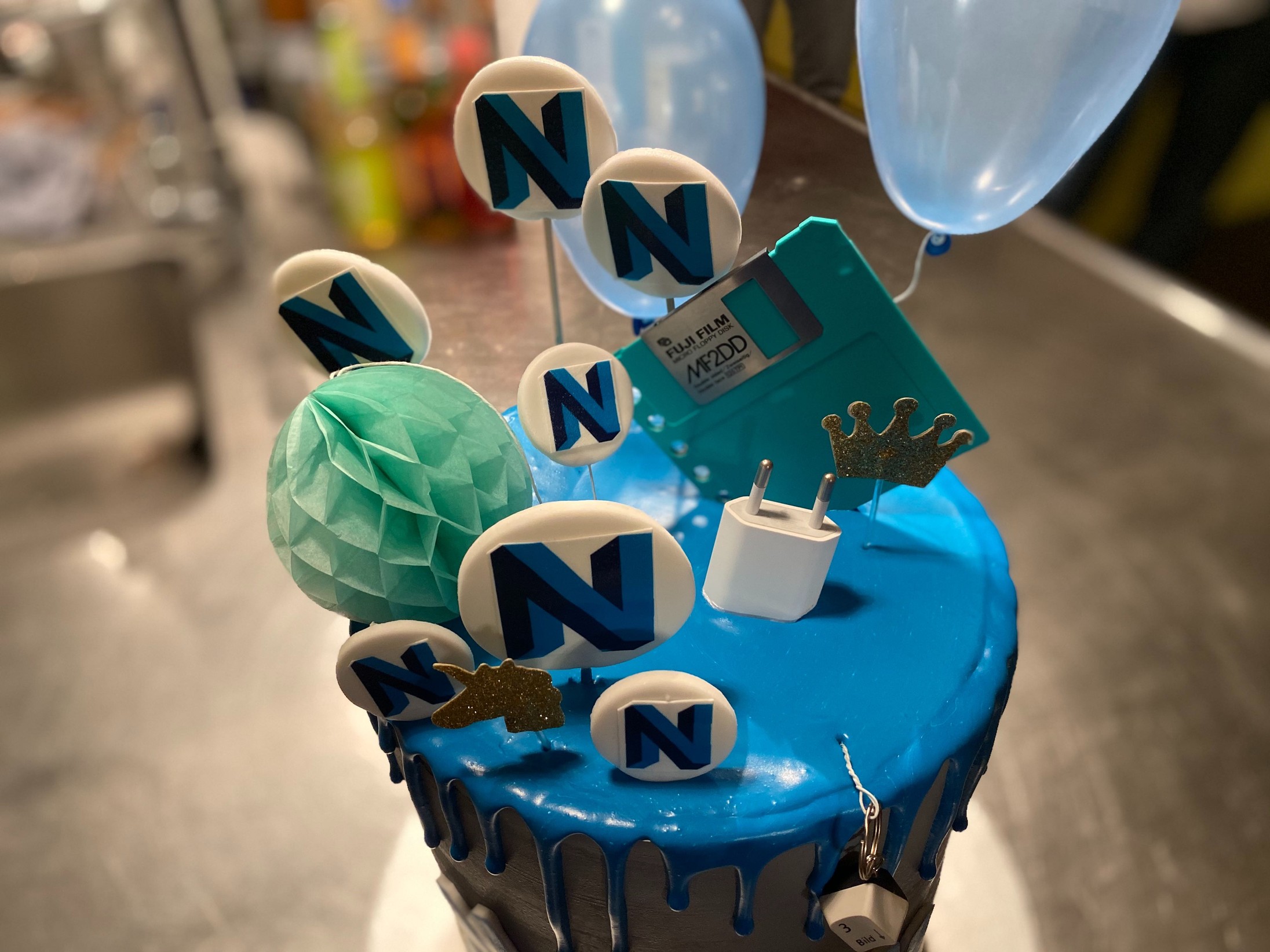 Cake with Neos logos, a phone charger and disk