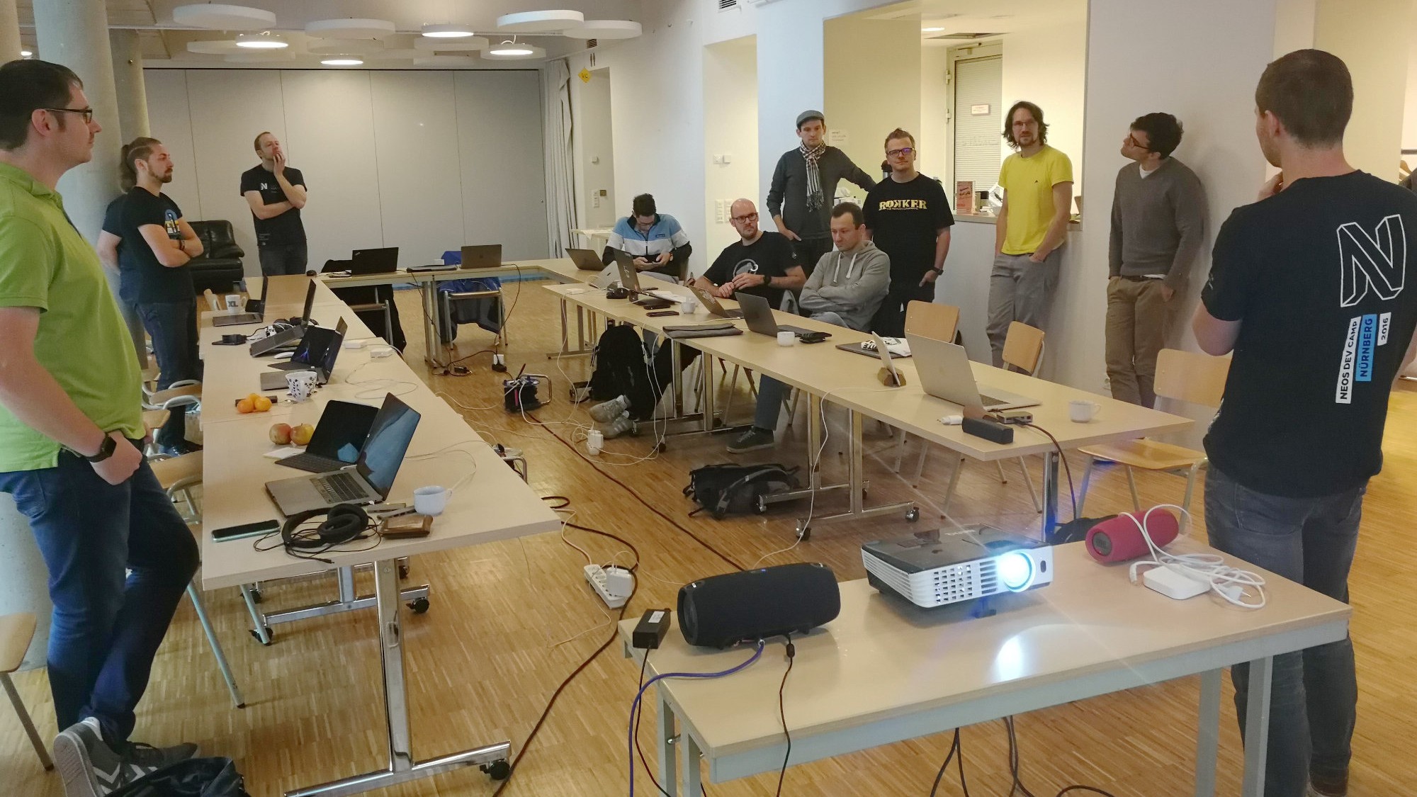 Neos community members standing around desks with laptops